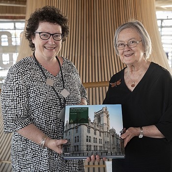 2 women in the Senedd holding a book